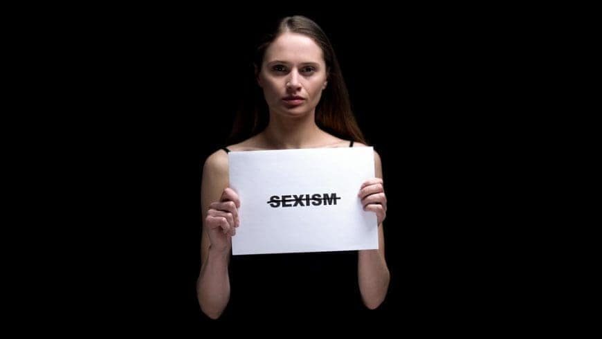 Woman holding a paper with "Sexism" crossed with a marker