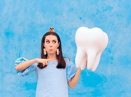 A woman holding a big tooth