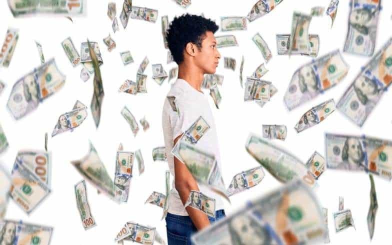 A young man standing with money all around him