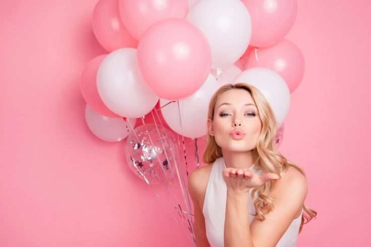 Woman holding pink and white balloons