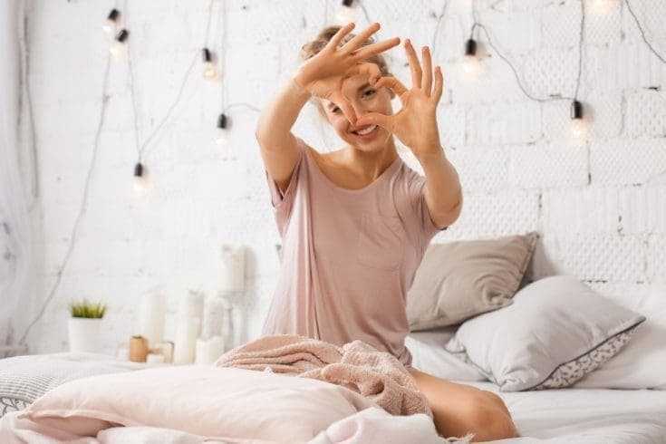 Get Everything You Want In Life - 5 Best Steps 9 A young woman sitting on the bed and making a heart with her hands. Get Everything You Want In Life