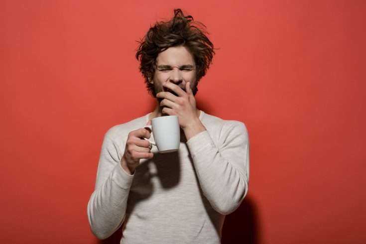 12 Signs You Are a Coffee Addict 9 Sleepy man holding a cup