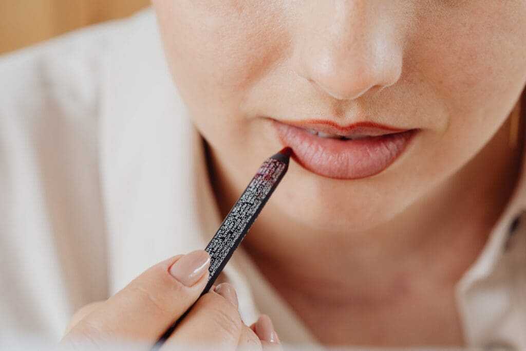 How to Do Makeup at Home (Best Guide of 2022) 20 Woman applying lip liner