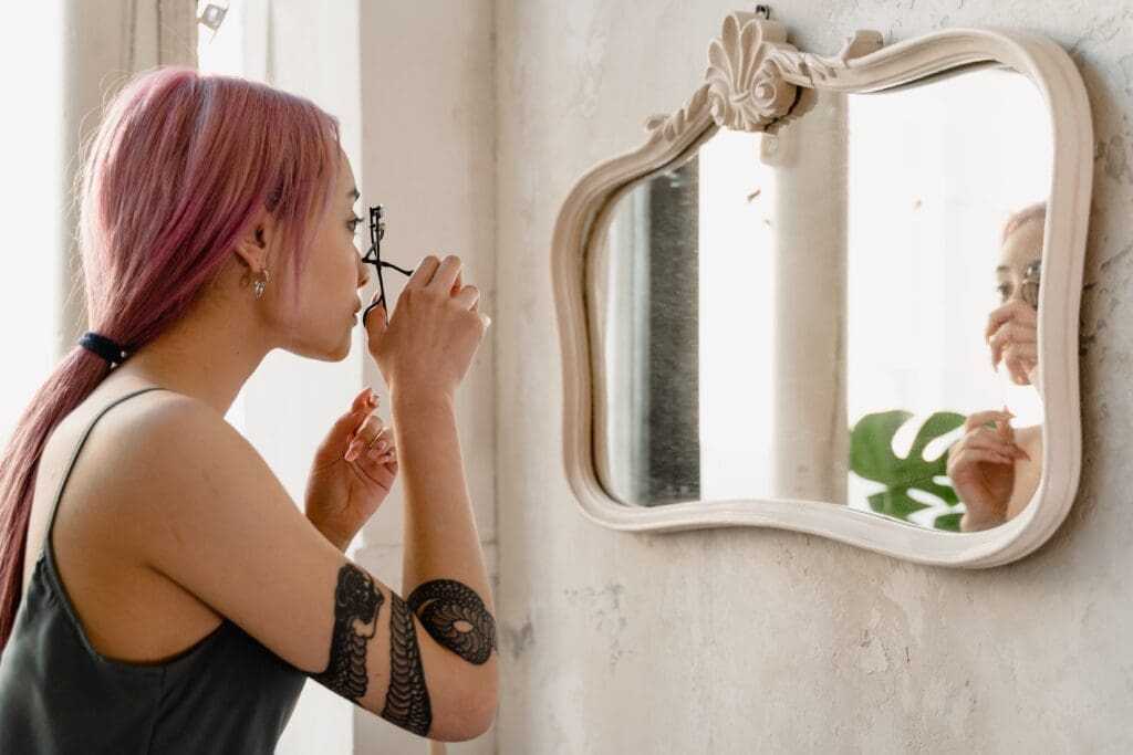 How to Do Makeup at Home (Best Guide of 2022) 18 woman curling her lashes