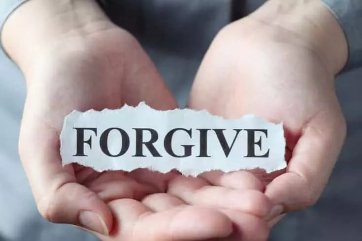 a person holding a paper withForgive written on it