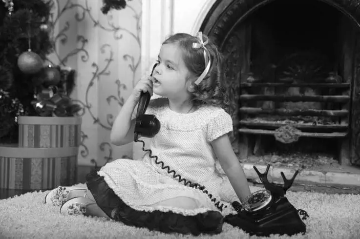 Black and white picture of a toddler talking on phone