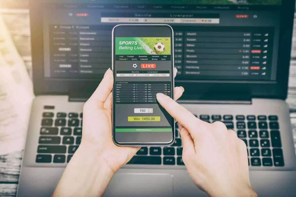 betting bet sport phone gamble laptop over shoulder soccer live home website concept - stock image.