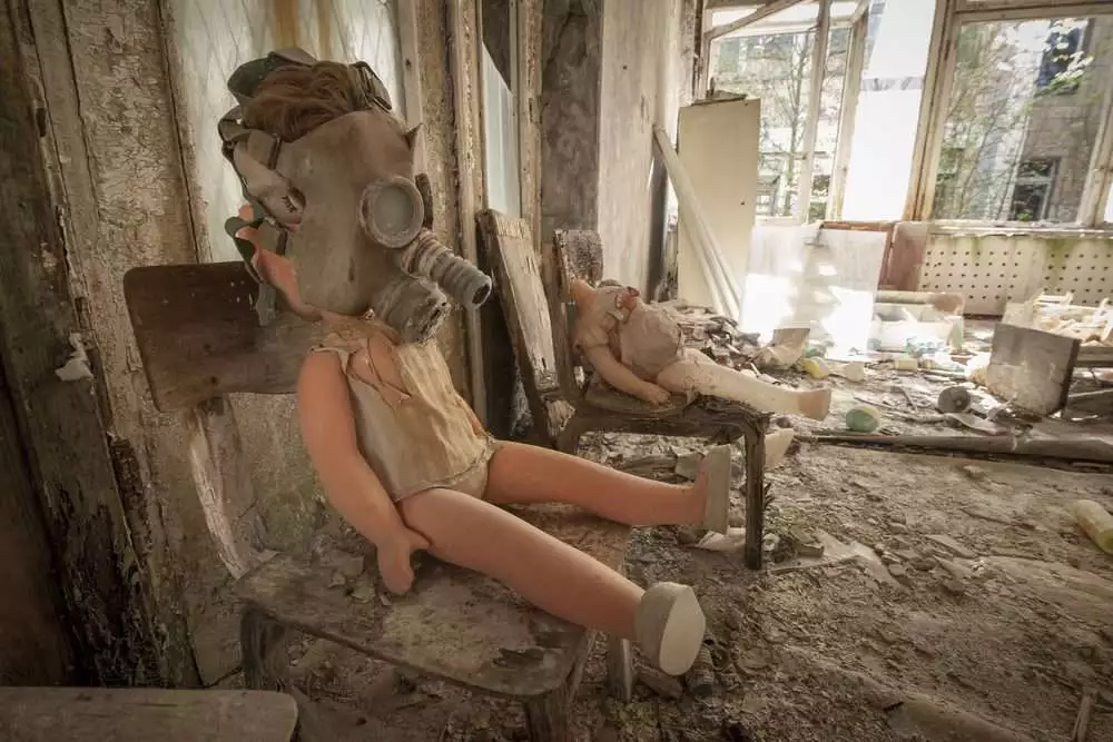 Old doll with a gas mask sitting on a chair in an abandoned kindergarten in Pripyat - Chernobyl nuclear power plant zone of alienation