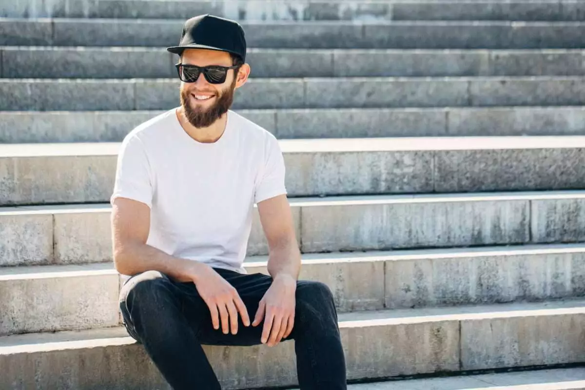 Hipster handsome male model with beard wearing white blank t-shirt with space for your logo or design in casual urban style.