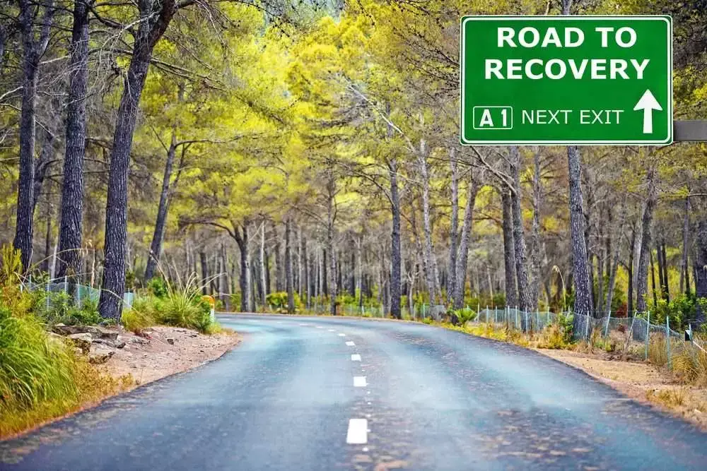 ROAD TO RECOVERY road sign against clear blue sky.
